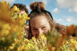 Chica sonriente disfrutando del sol entre plantas, simbolizando la conexión con la naturaleza en nuestros eventos de wellness y meditación en Barcelona
