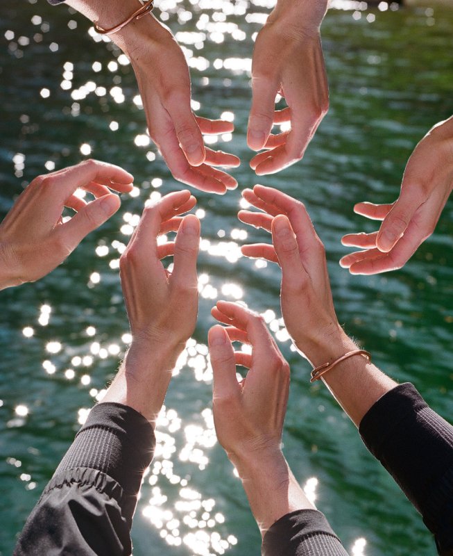 Personas juntando sus manos sobre agua, simbolizando la unidad y el compromiso compartido en nuestros retiros de bienestar y meditación en Barcelona.